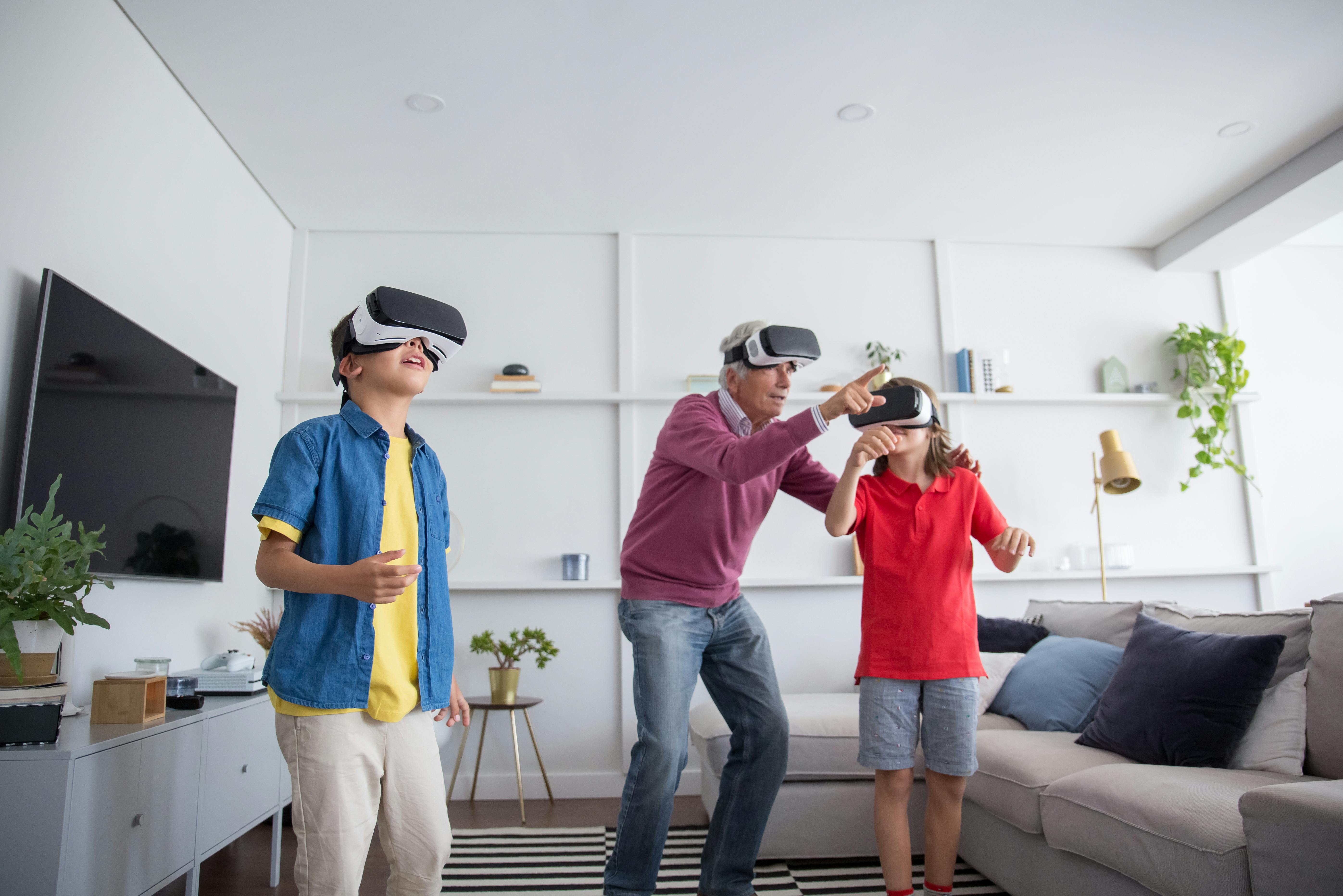 grandfather playing a video game using virtual reality goggles with his grandchildren