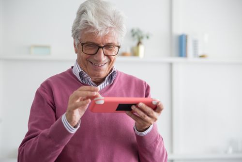 Free Elderly man with white hair and glasses, enjoying a game on a smartphone. Stock Photo