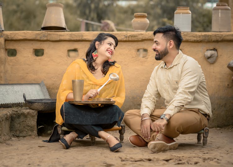 Couple Preparing Meal Outdoors Sitting On Ground