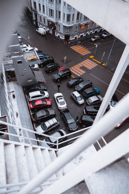 Overhead shot of a crowded urban parking lot with various cars parked densely.