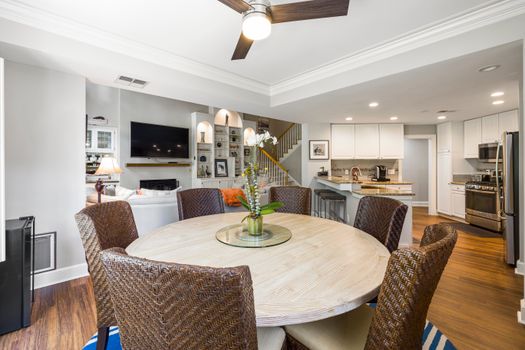 Bright dining room with wicker chairs and a round table, blending modern design with comfort.