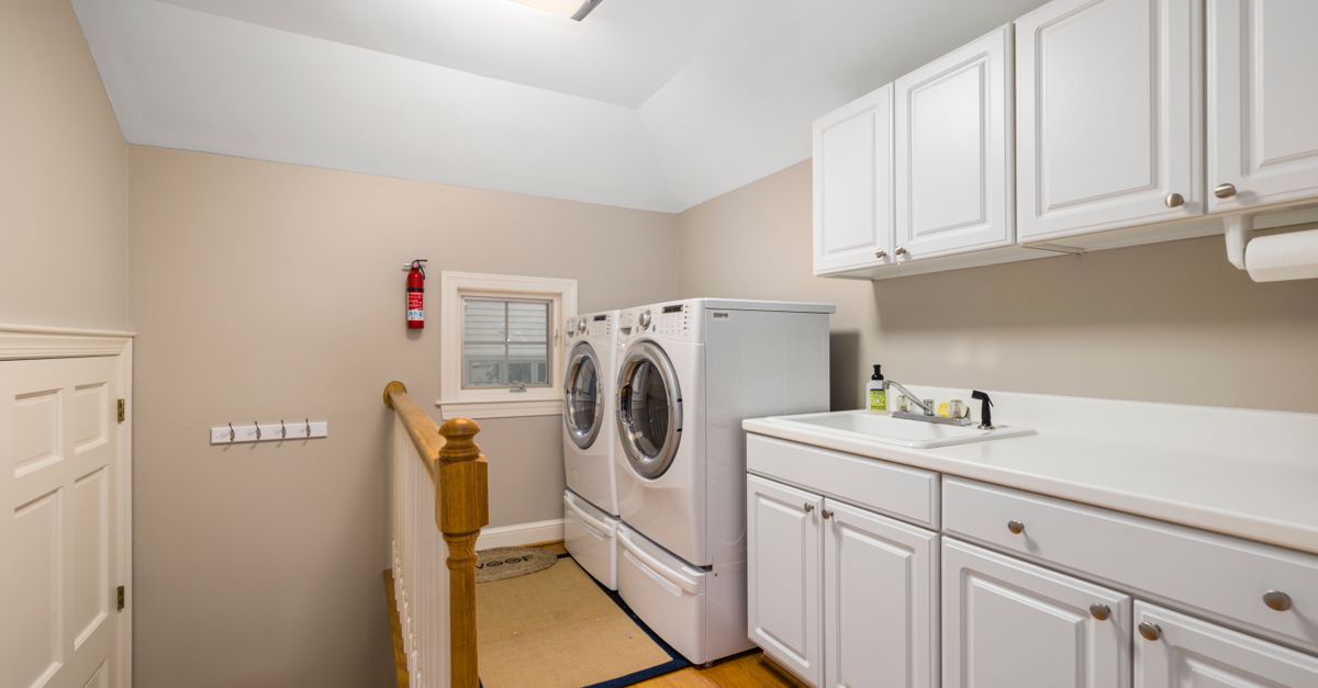 Spacious and clean laundry room featuring modern appliances and white cabinetry.