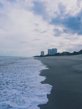 Tranquil ocean view at Río Hato, Panama, with waves gently reaching the shore under a cloudy sky.