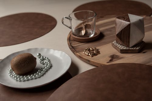 Kiwi and a String of Pearls on a Ceramic Plate with a Wooden Tray and Glass 