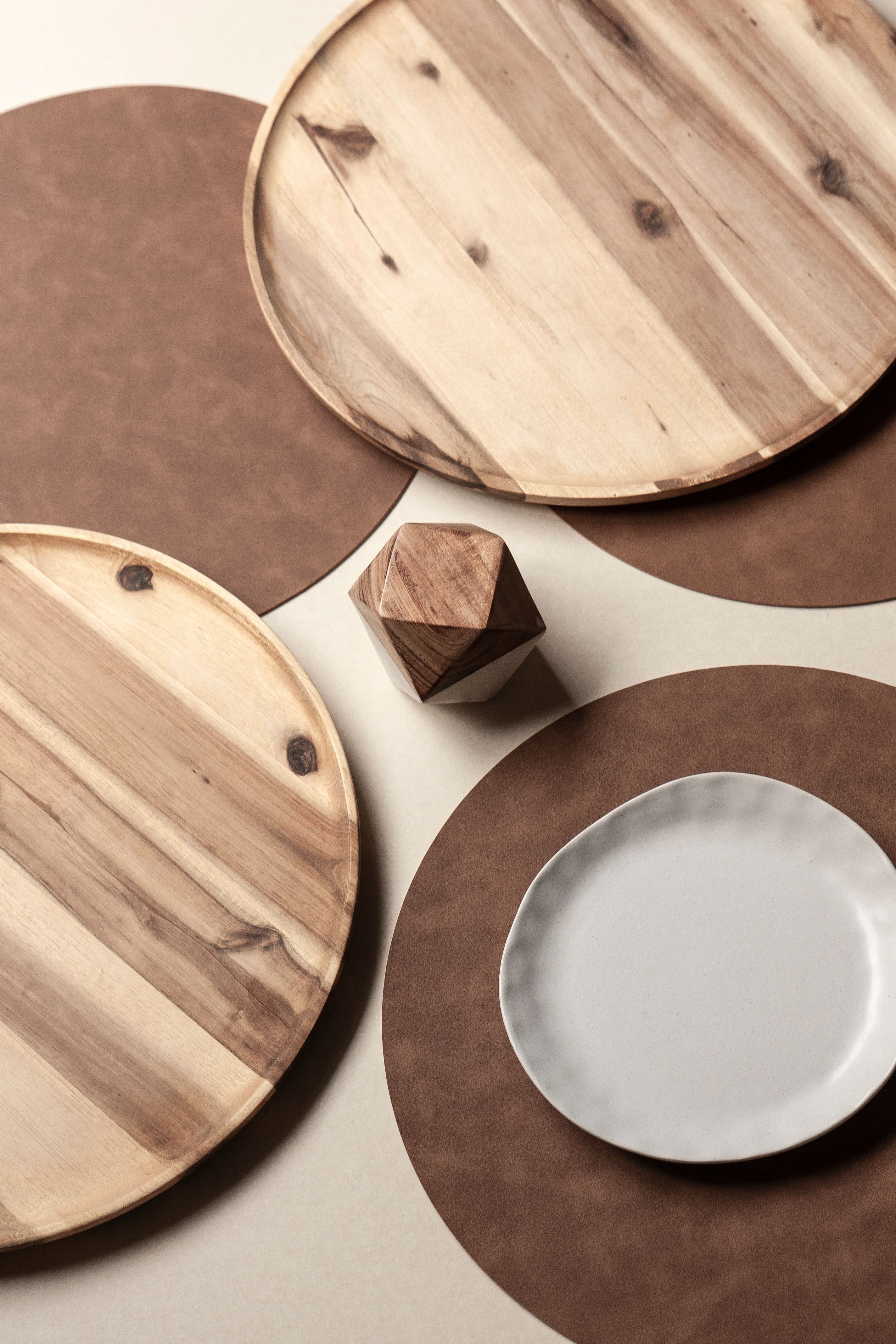 Top view of a minimalist table setting with wooden trays and a ceramic plate.