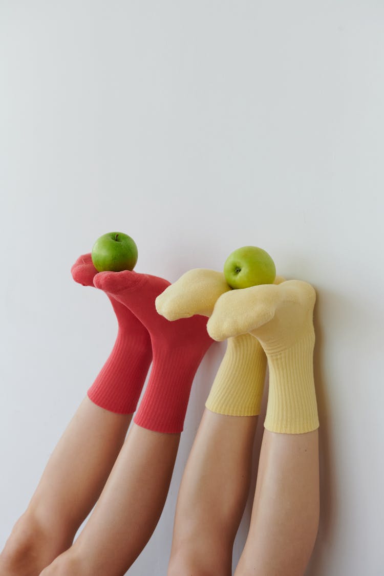 Two People Balancing Apples On Their Feet 