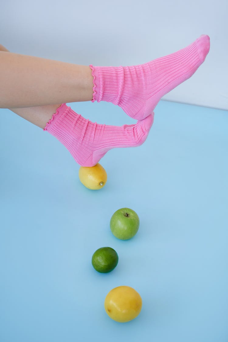 Feet In Pink Socks Resting On Lemon