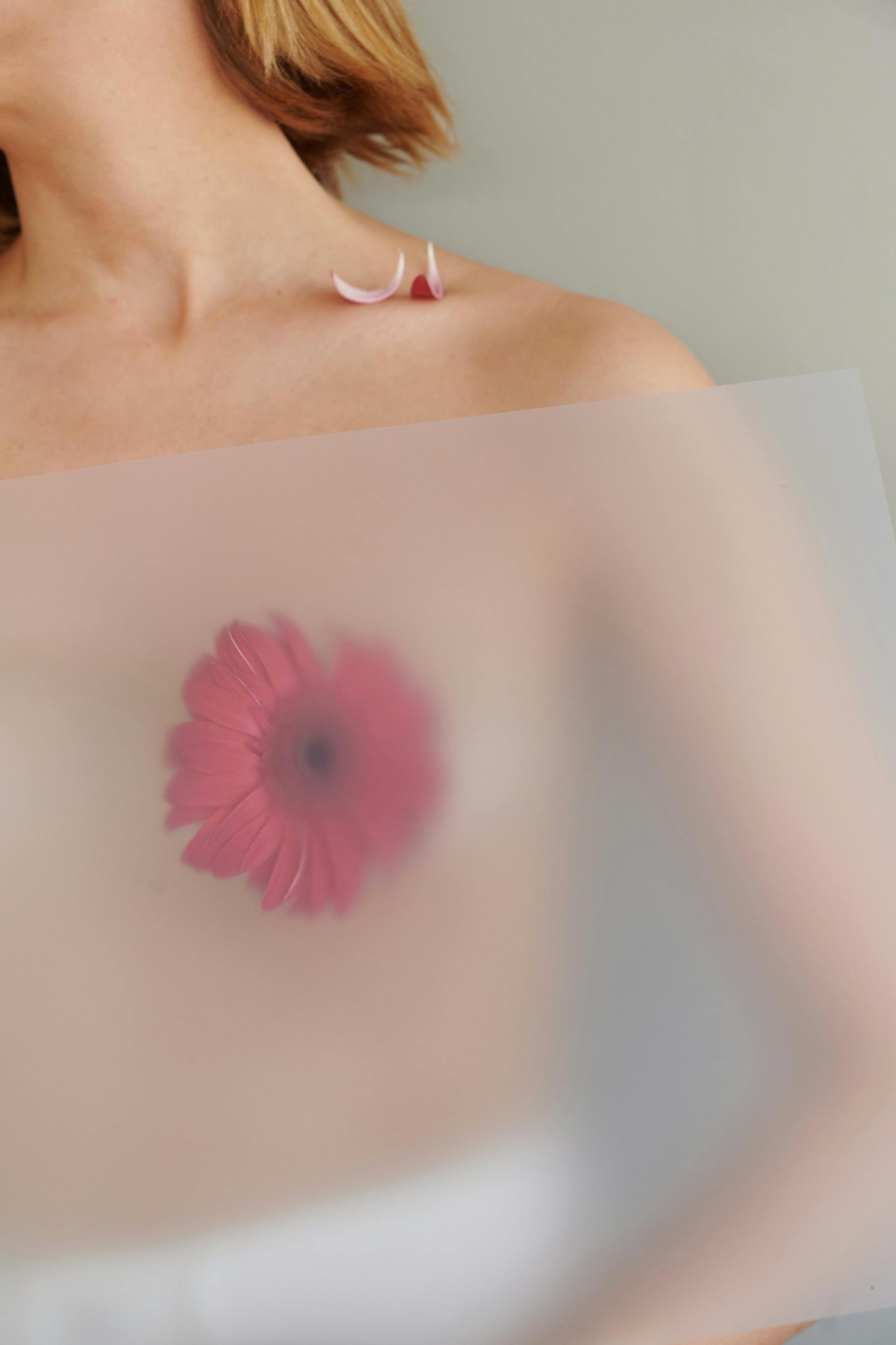 topless woman behind frosted glass with flower on her breast