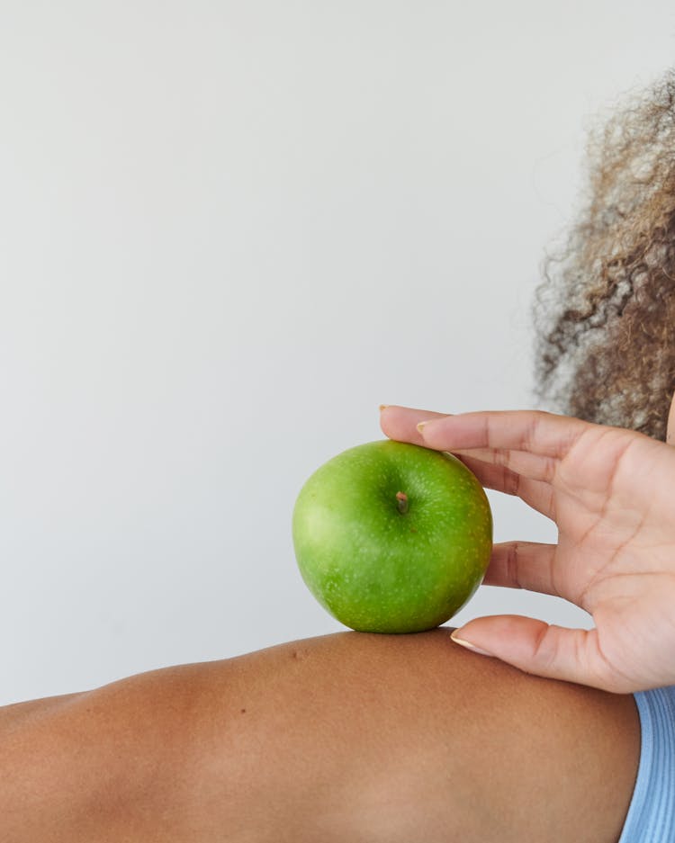 Close Up Of A Woman Holding Green Apple On Her Arm