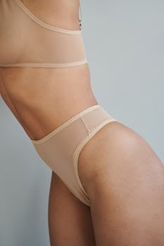 A close-up shot of a woman wearing nude lingerie, emphasizing body curves in soft lighting.