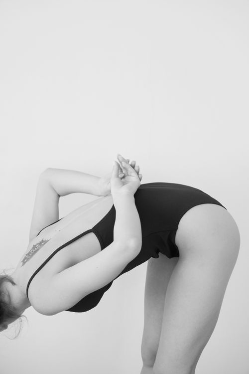 Free Elegant black and white photo of a woman posing in a bodysuit with hands behind back. Stock Photo