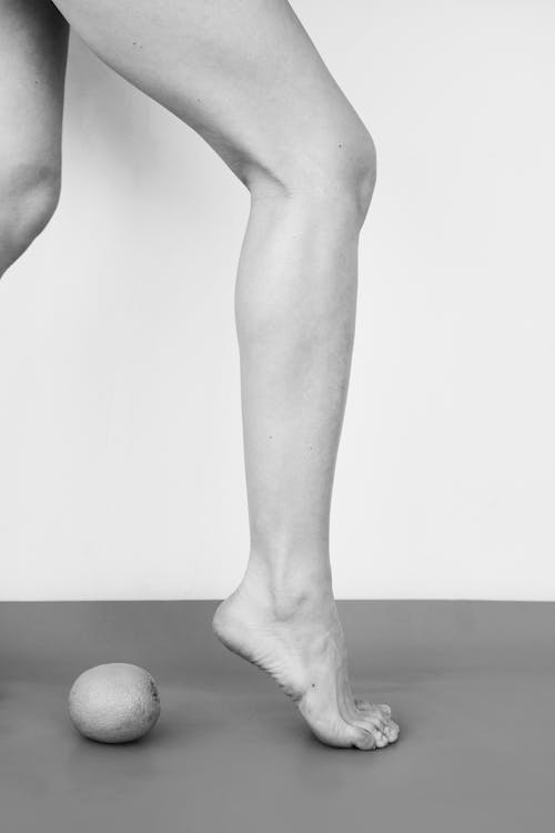 Grayscale Image of Female Legs and a Fruit · Free Stock Photo