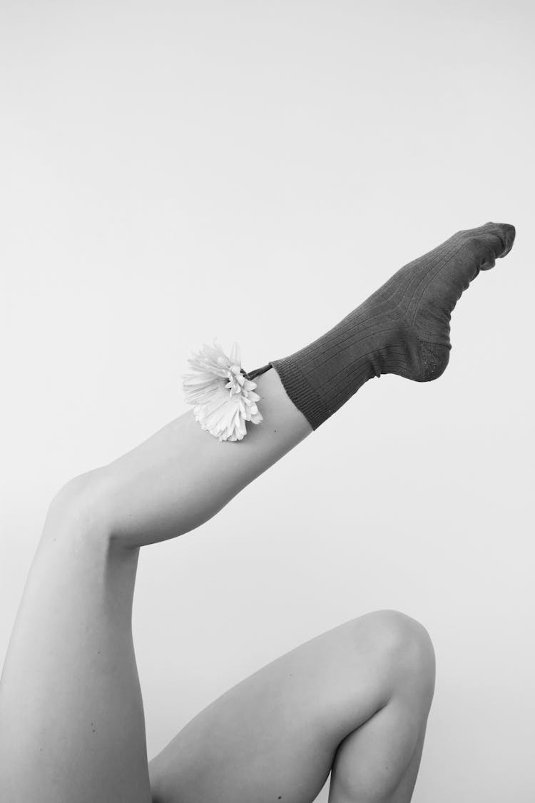 Grayscale Photo Of A Female Leg In A Sock With Flower