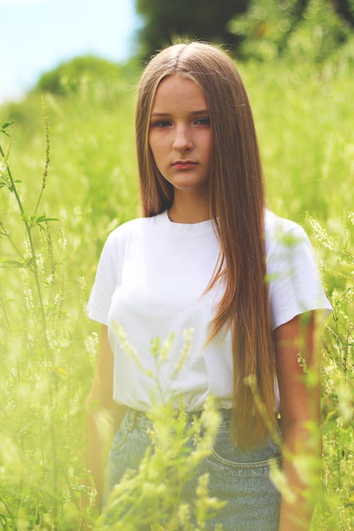 Woman Wearing White Shirt and Gray Denim Bottoms on Green Grass Field