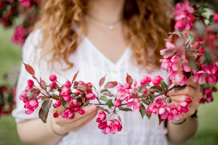 Woman Holding A Cluster Of Fuchsia Colored Flowers