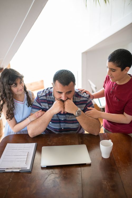 Free Father with daughter and son gathering around a laptop at home, spending quality family time. Stock Photo