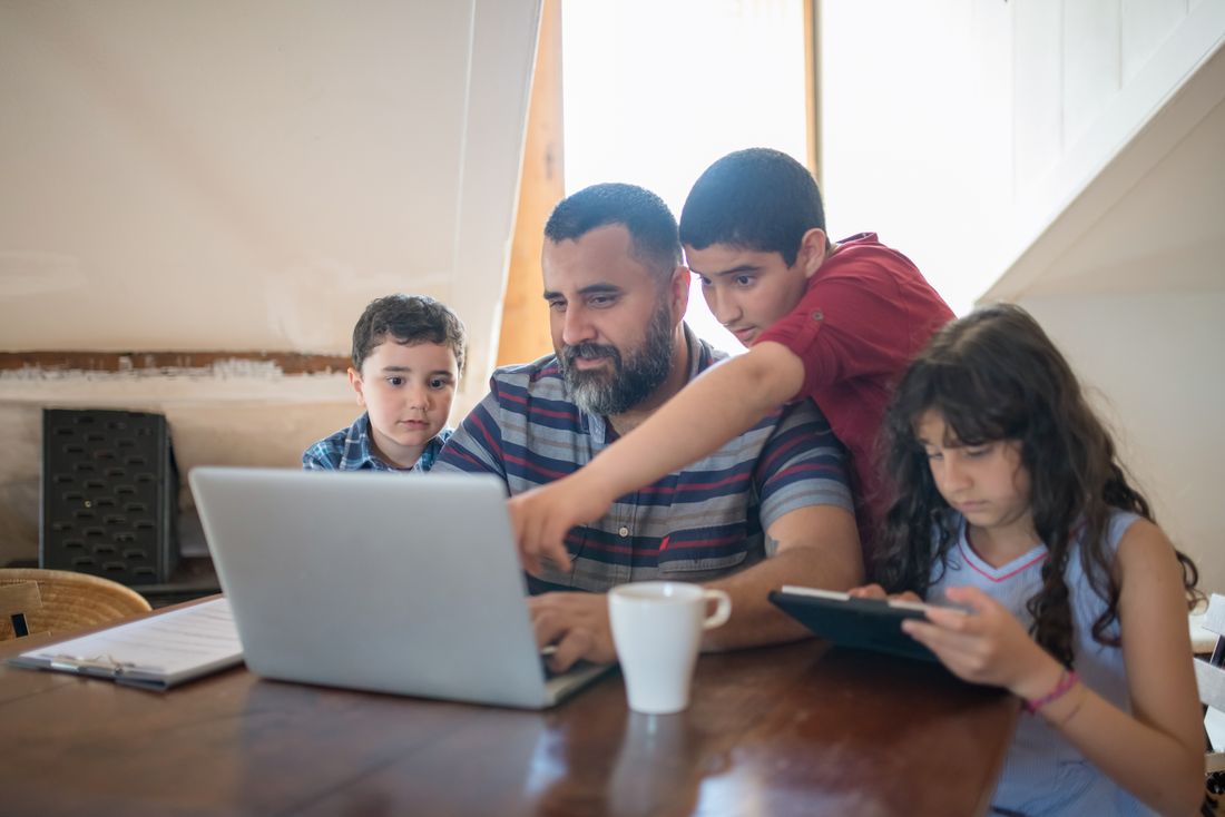 Dad helping his children with their homework at a laptop