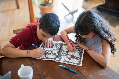 Free Two children color in a book at home, fostering creativity and family bonding. Stock Photo