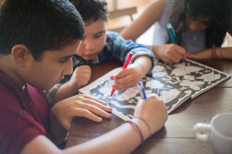 Children Working On An Activity Book Together