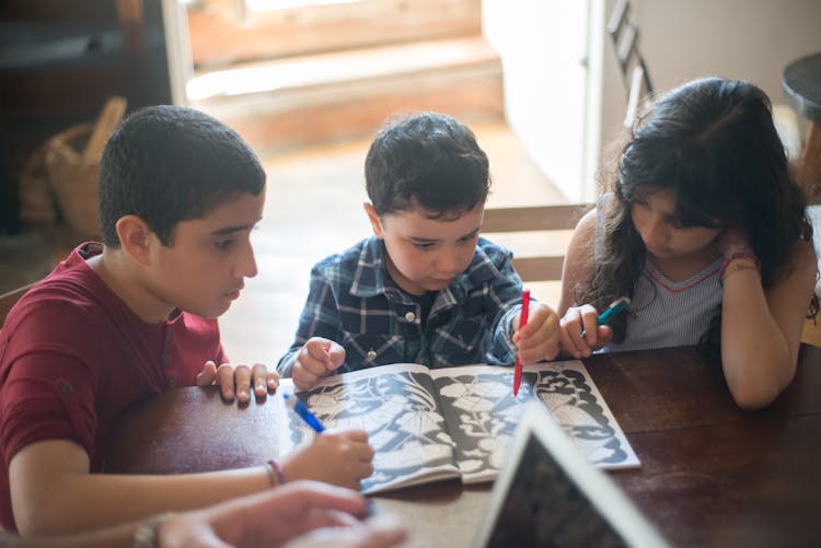 Children Working On An Activity Book Together