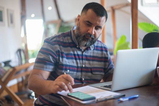 Professional man working at home office in Portugal using laptop and phone.