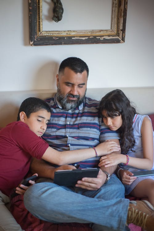 A Man Using a Tablet beside his Kids