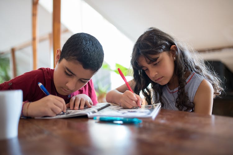 Children Working On An Activity Book Together