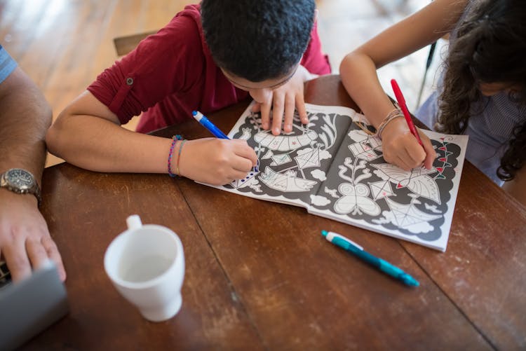 Children Working On An Activity Book Together