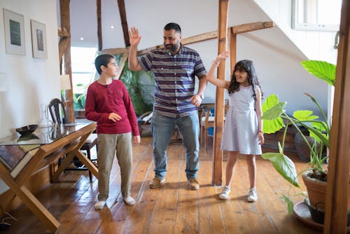 A Man and his Daughter Trying to do a High Five with his Son