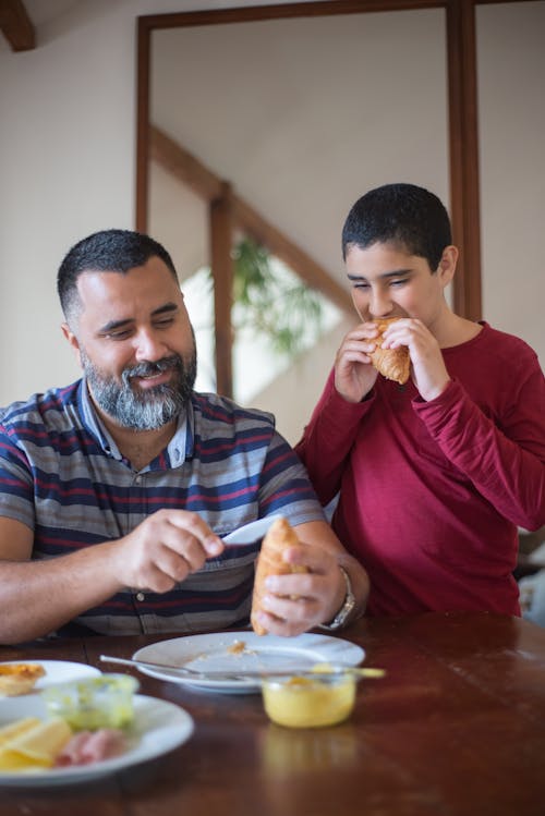 A Boy Eating a Croissant with his Father