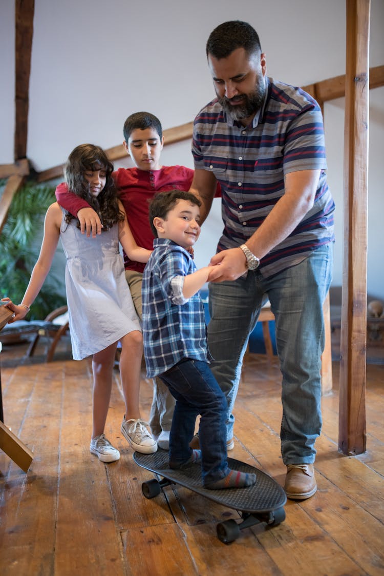 A Father Teaching His Son To Ride A Longboard