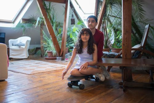 Free Young boy and girl having fun on a longboard in a cozy indoor space. Stock Photo