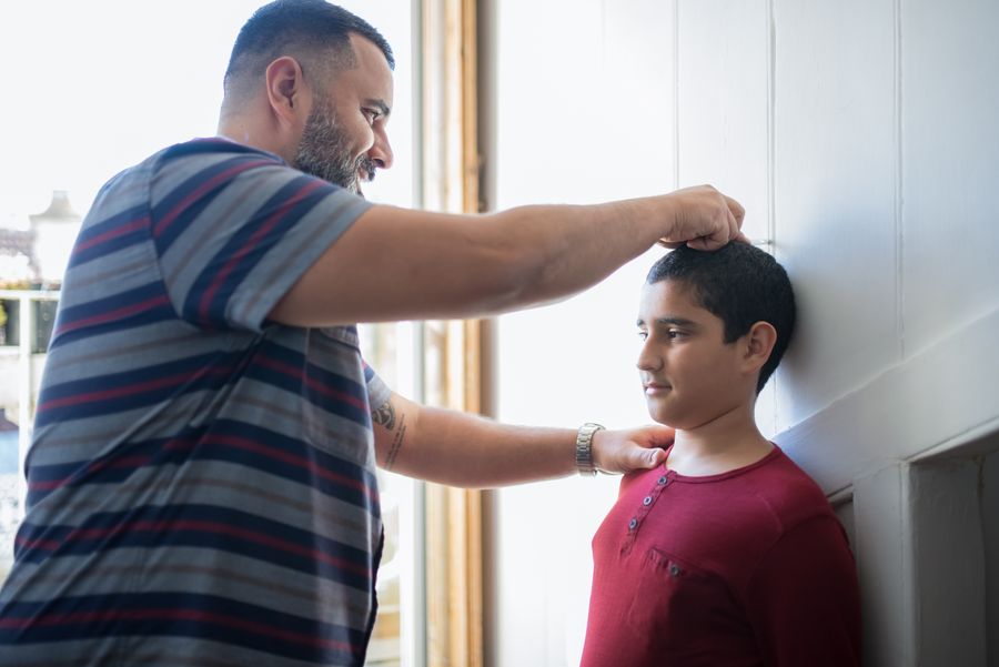 A father measuring his son's height against a wall