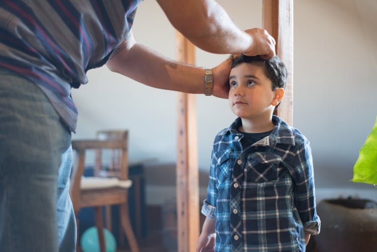 Father Measuring Height Of His Son 