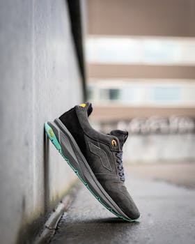 Close-up of a black suede sneaker leaning against a wall in an urban setting.