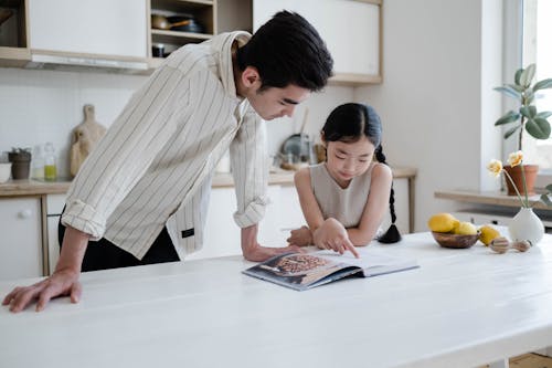 A Girl Looking at a Cook Book with her Father
