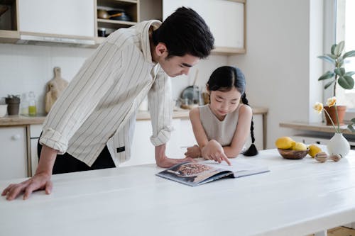 Free A Girl Looking at a Cook Book with her Father Stock Photo