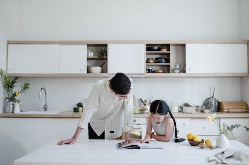 Free A Girl Looking at a Cook Book with her Father Stock Photo