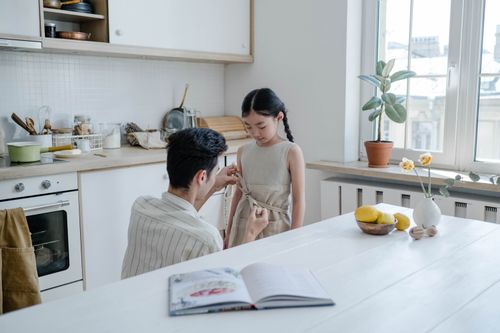 Free A father and daughter bonding in the kitchen, wearing aprons and preparing to cook together. Stock Photo