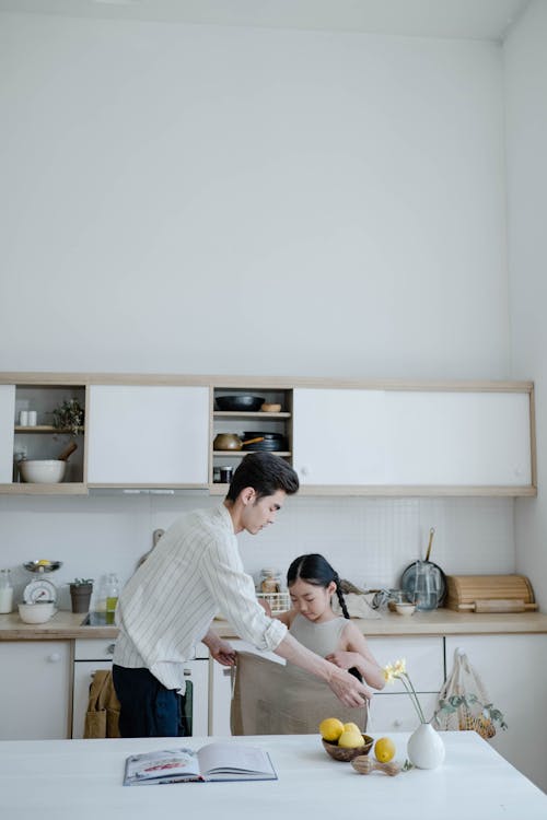 Free Father and Daughter Holding a Towel in the Kitchen Stock Photo