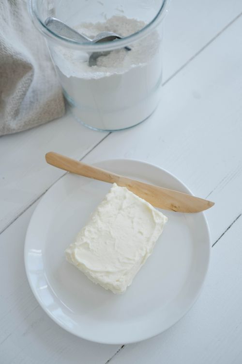 Free A close-up of white butter on a plate with a wooden knife, set for spreading. Stock Photo