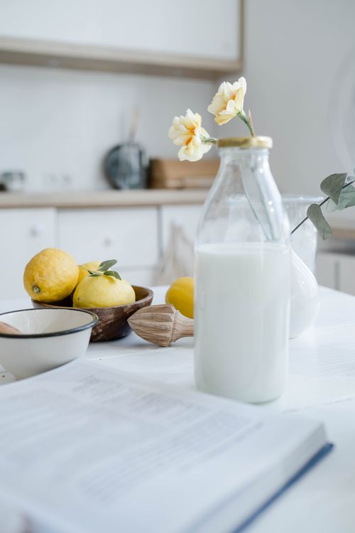 Free A serene kitchen scene featuring lemons, milk, and flowers. Stock Photo