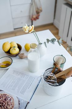 A cozy kitchen scene featuring lemons, a glass of milk, and kitchen utensils.