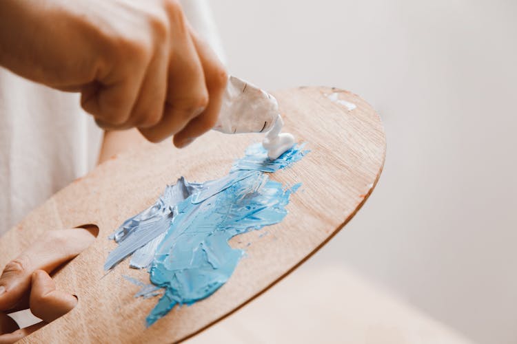 Person Mixing Paint On Wooden Palette