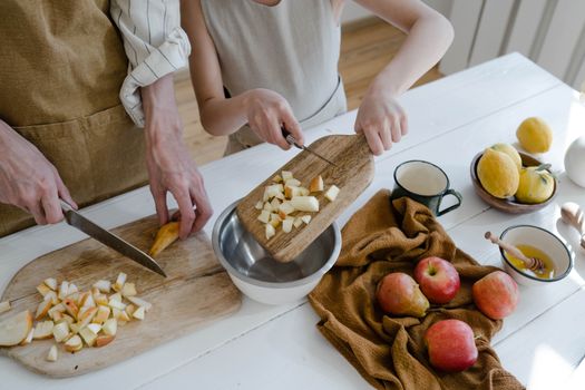 Father and daughter chopping apples and citrus fruits at home for a healthy family meal.