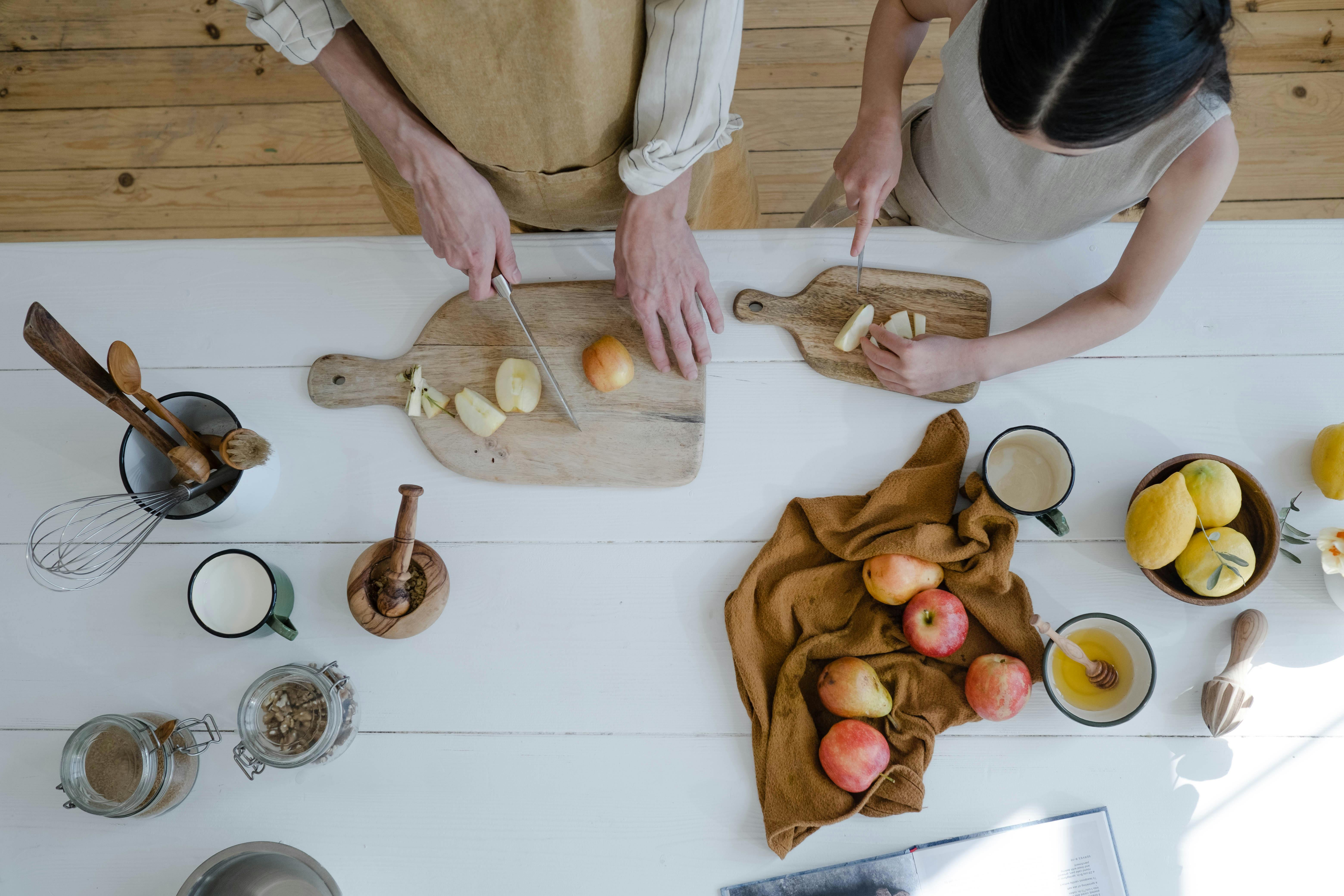 High-Angle Shot of a Man and a Young Girl Slicing Apples on a Wooden Chopping Boards