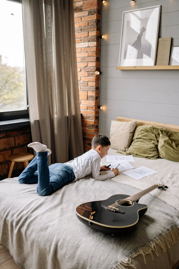 A Boy On The Bed Writing In The Paper