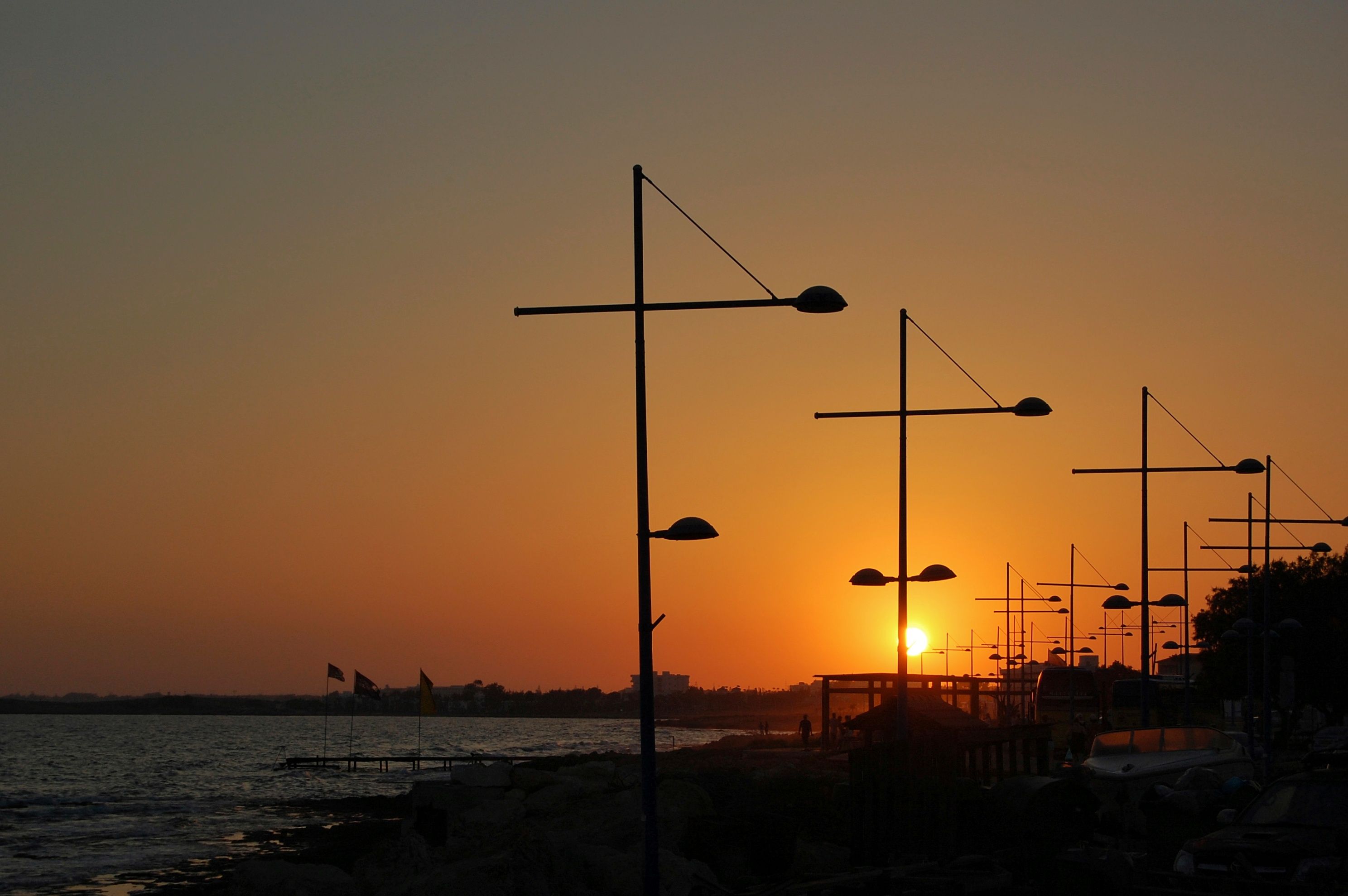 Enjoy a picturesque sunset view with silhouetted streetlights along the Ayia Napa waterfront. - Photo by Mia Ross on Pexels