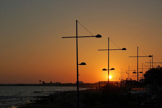 Enjoy a picturesque sunset view with silhouetted streetlights along the Ayia Napa waterfront.