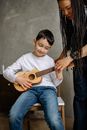 Boy in White Crew Neck T-shirt Playing Brown Acoustic Guitar